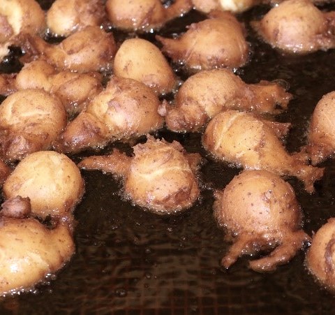 Nahaufnahme von zahlreichen Teigbällchen, die im Fett gebacken werden.
