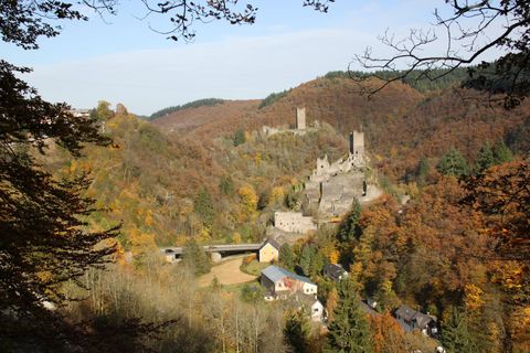 Aussicht auf die Manderscheider Burgen im Herbst mit buntem Laub und umliegenden Hügeln.