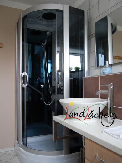 Ein modernes Badezimmer mit einer gläsernen Dusche und einem stilvollen Waschbecken. Die Einrichtung ist funktional und ansprechend gestaltet.