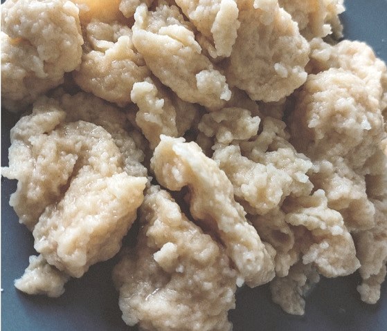 Several differently shaped dough dumplings are stacked on top of each other in a bowl.