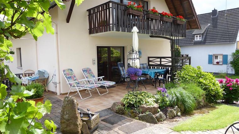 Ein gemütlicher Außenbereich mit einem Balkon und bunten Blumen. Es gibt Liegen und einen Tisch, um die Natur zu genießen.