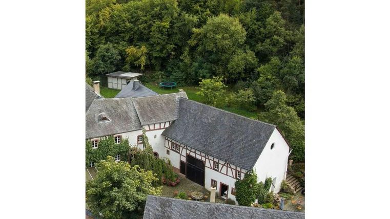Ein malerisches Bauernhaus umgeben von Bäumen und Grünflächen. Die harmonische Architektur entsteht durch die Kombination von traditionellem und modernem Design.
