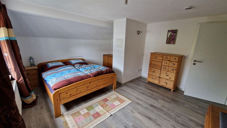 Une chambre confortable avec un lit double et des armoires en bois. La pièce a des murs clairs et un revêtement de sol moderne.