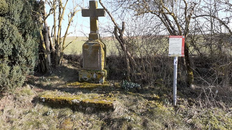 Wegekreuz bei Auel mit Infotafel und Bäumen im Hintergrund.
