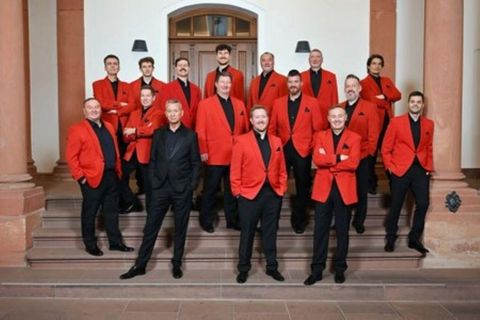 Eine Gruppe Männer in roten Anzügen steht auf einer Treppe und lächelt