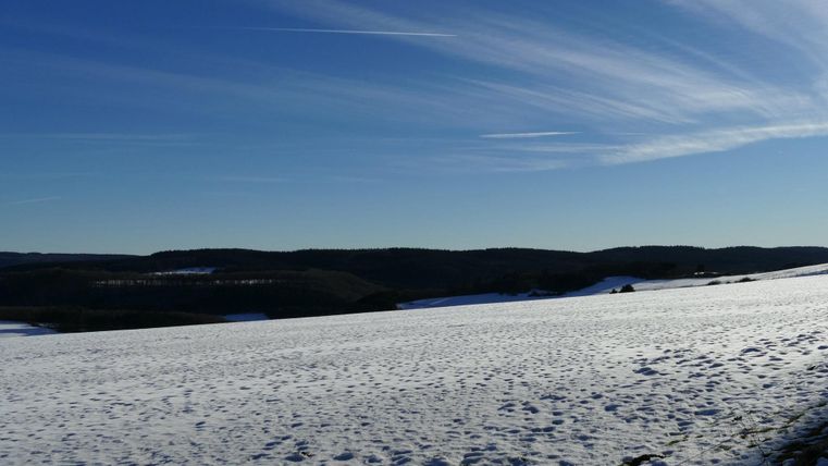 Un paysage enneigé sous un ciel bleu clair. De douces collines sont visibles à l'arrière-plan.