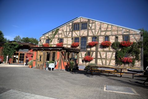 Un bâtiment charmant de style à colombages avec des jardinières rouges. L'entrée est accueillante et les environs sont bien entretenus.