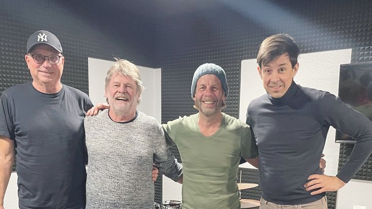 Gruppenbild derMusiker. Sie stehen Arm in Arm in einem Tonstudio