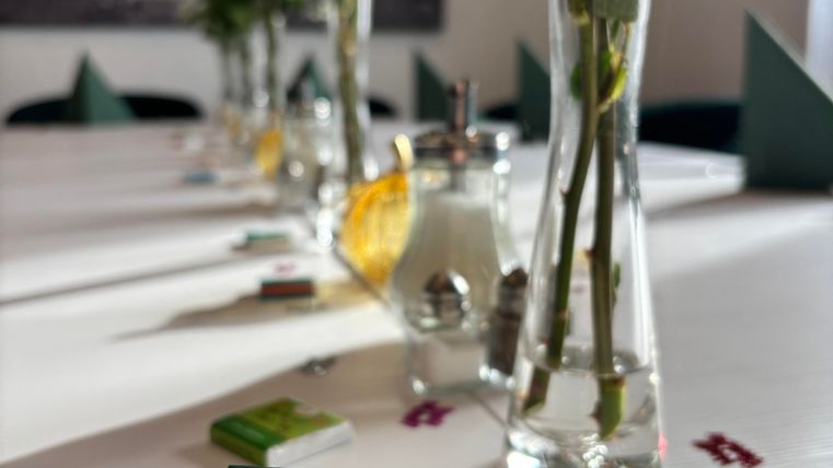 Ein festlich gedeckter Tisch mit mehreren Blumenvasen und einer Karte, auf der steht: "HEUTE GEHT ES NURUM DICH-TAG." Die Atmosphäre wirkt einladend und freundlich.