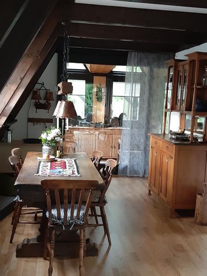 Ein gemütlicher Essbereich mit einem großen Holztisch und Stühlen. Die warmen Holz-Elemente und das natürliche Licht schaffen eine einladende Atmosphäre.