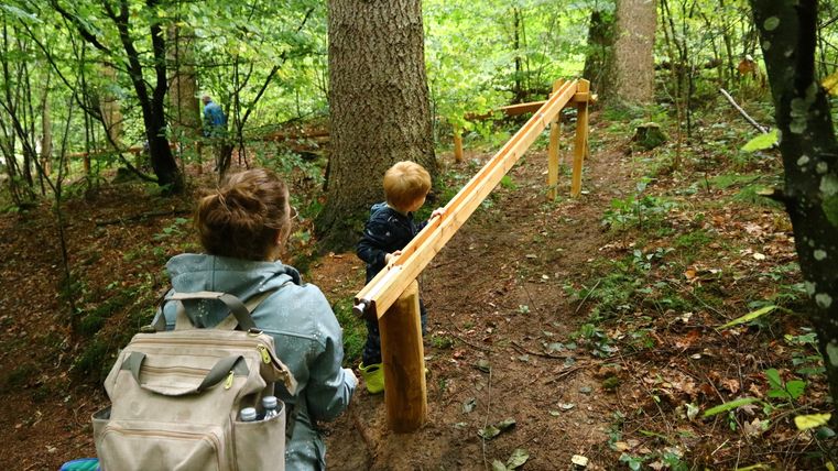 Eine Mutter und ihr Kind spielen an einer Katapultstation der Waldkugelbahn Gerolstein.