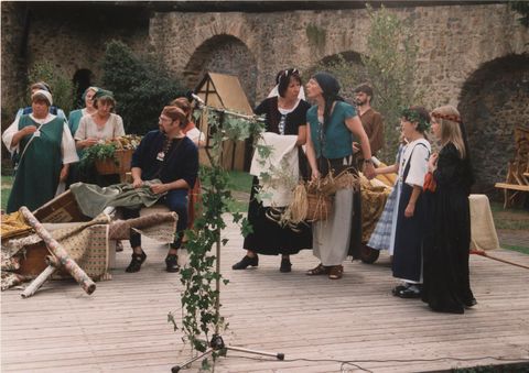 Zu sehen ist eine hölzerne Bühne. Darauf stehen leute in traditioneller Kleidung.