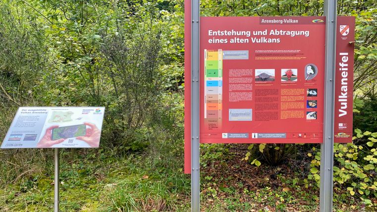 Two information signs in the countryside, one about the Arensberg volcano and one about the Volcanic Eifel.