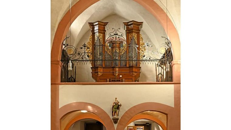 Eine prächtige Orgel in einer Kirche mit hohen Gewölben. Die Holzverarbeitung und kunstvollen Verzierungen sind gut erkennbar.