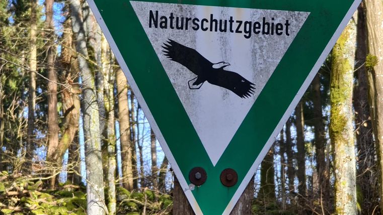 Un panneau de signalisation portant l'inscription "Réserve naturelle". Il montre un aigle stylisé devant un arrière-plan forestier.