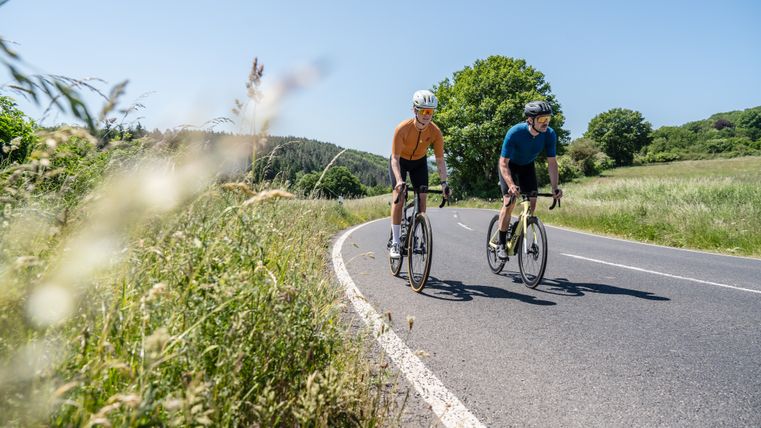 Zwei Radfahrer auf einer Landstraße in der Eifel.