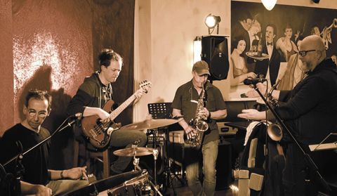 Un groupe de jazz joue dans un club confortable. Les musiciens apprécient l'atmosphère et prennent soin de leurs instruments.